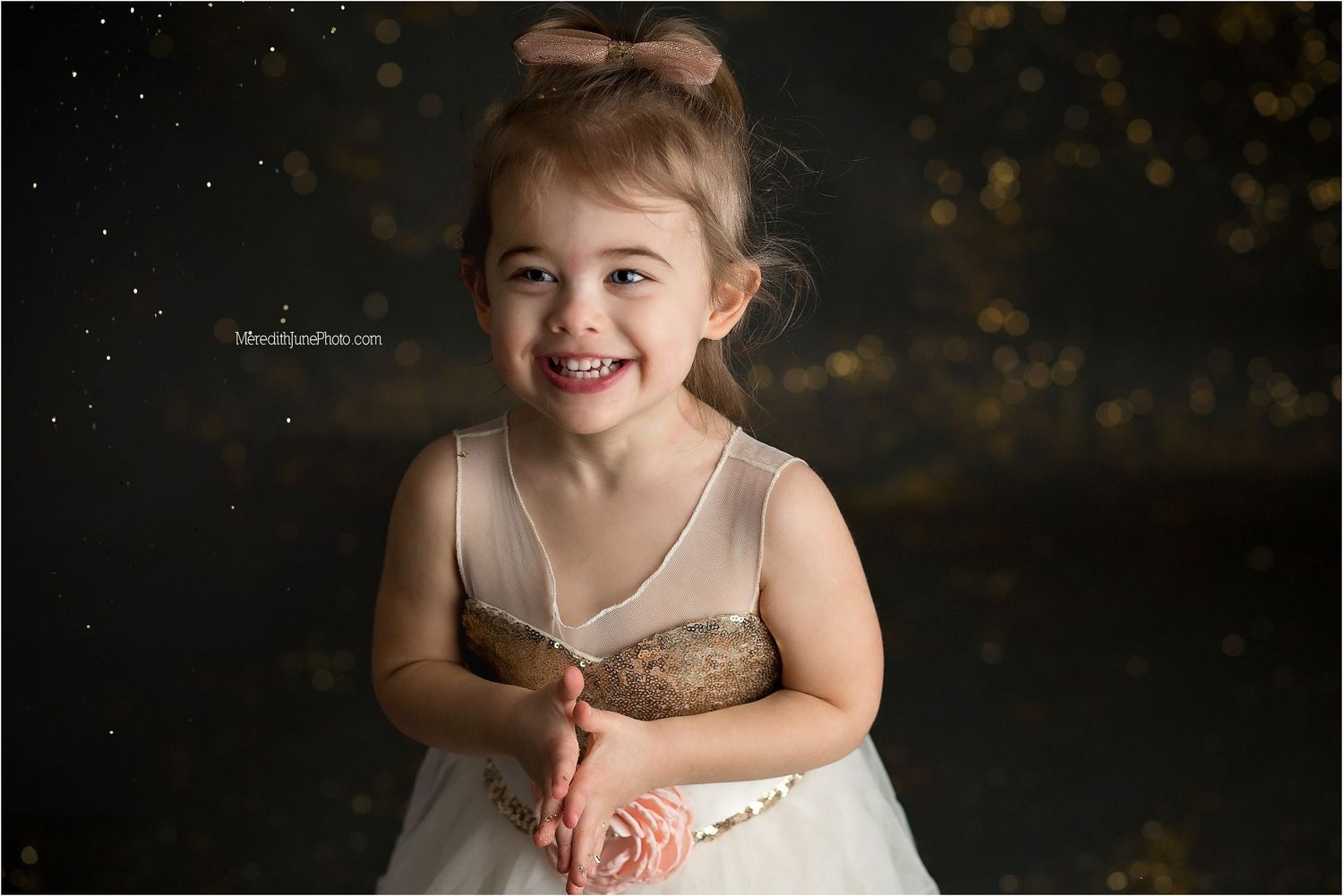 A child wearing a sparkly gold dress twirls and dances in front of a dark background.