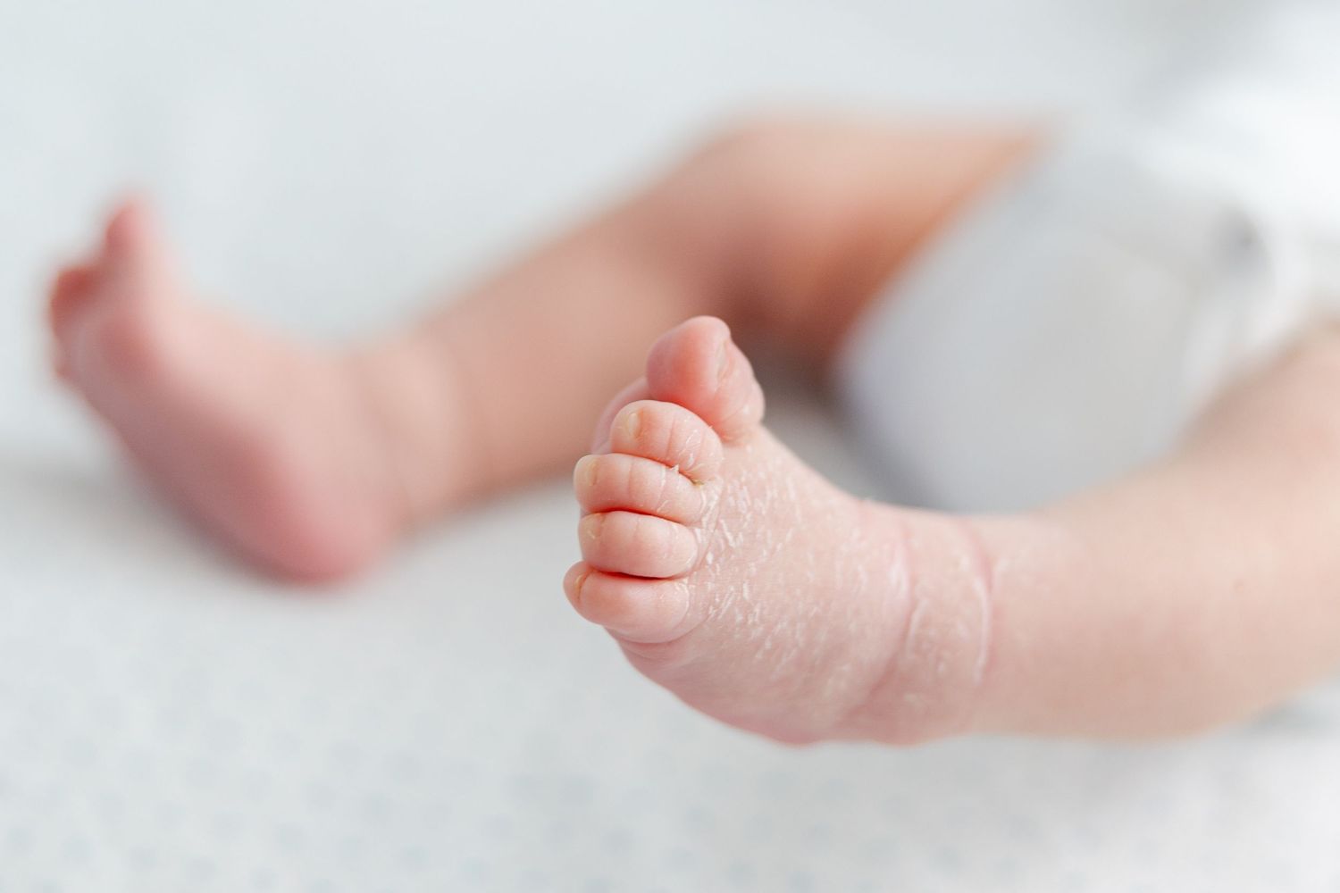 Close-up view of tiny baby toes and feet on white background.