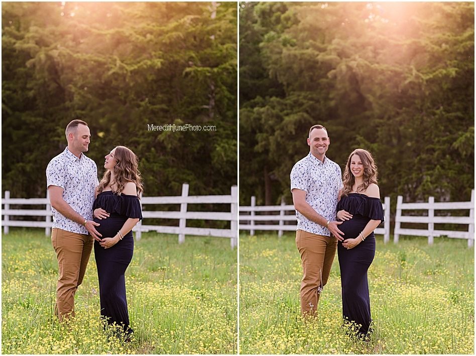 A couple in a field embraces during sunset with a white fence in the background.