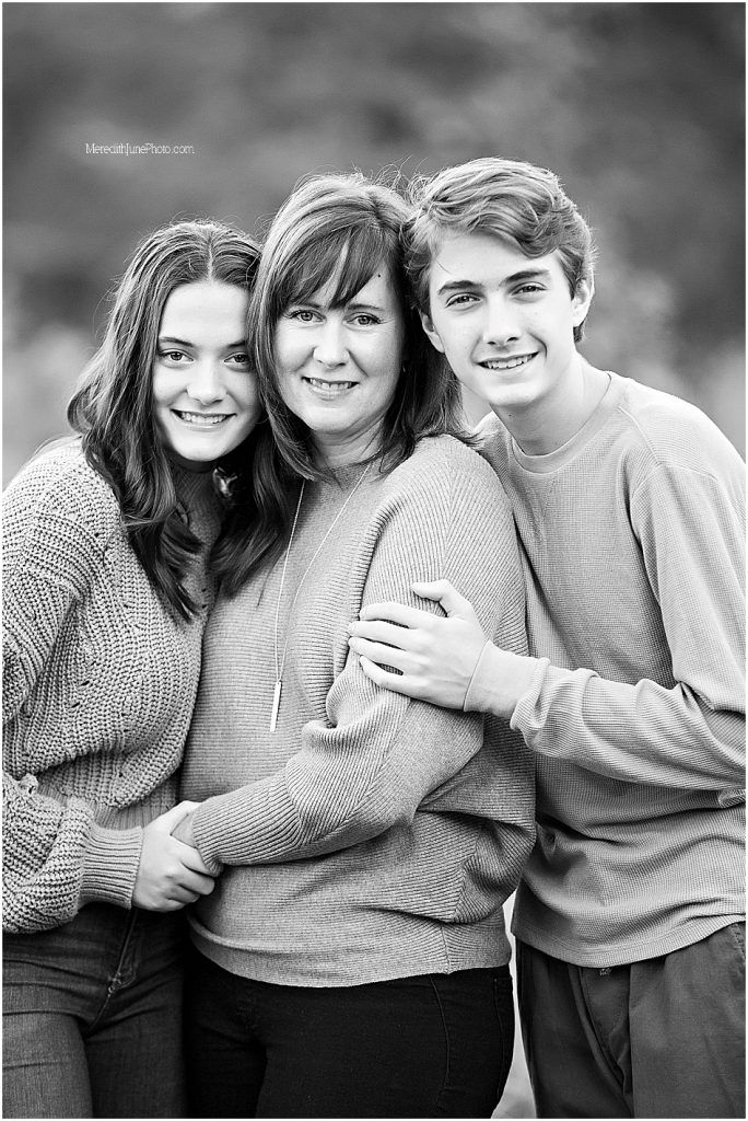 Black and white portraits showing three people embracing and smiling together.