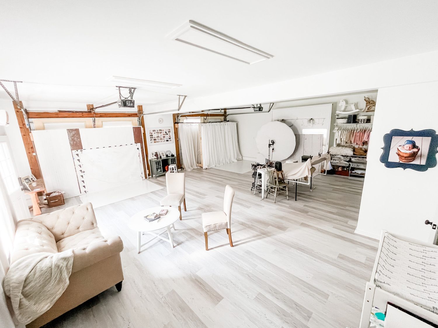 A bright white modern bedroom with minimalist decor features gray hardwood floors and natural light streaming through windows.