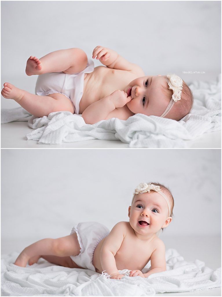 Sweet baby in white diaper and headband lying on soft white blanket during professional photo session.