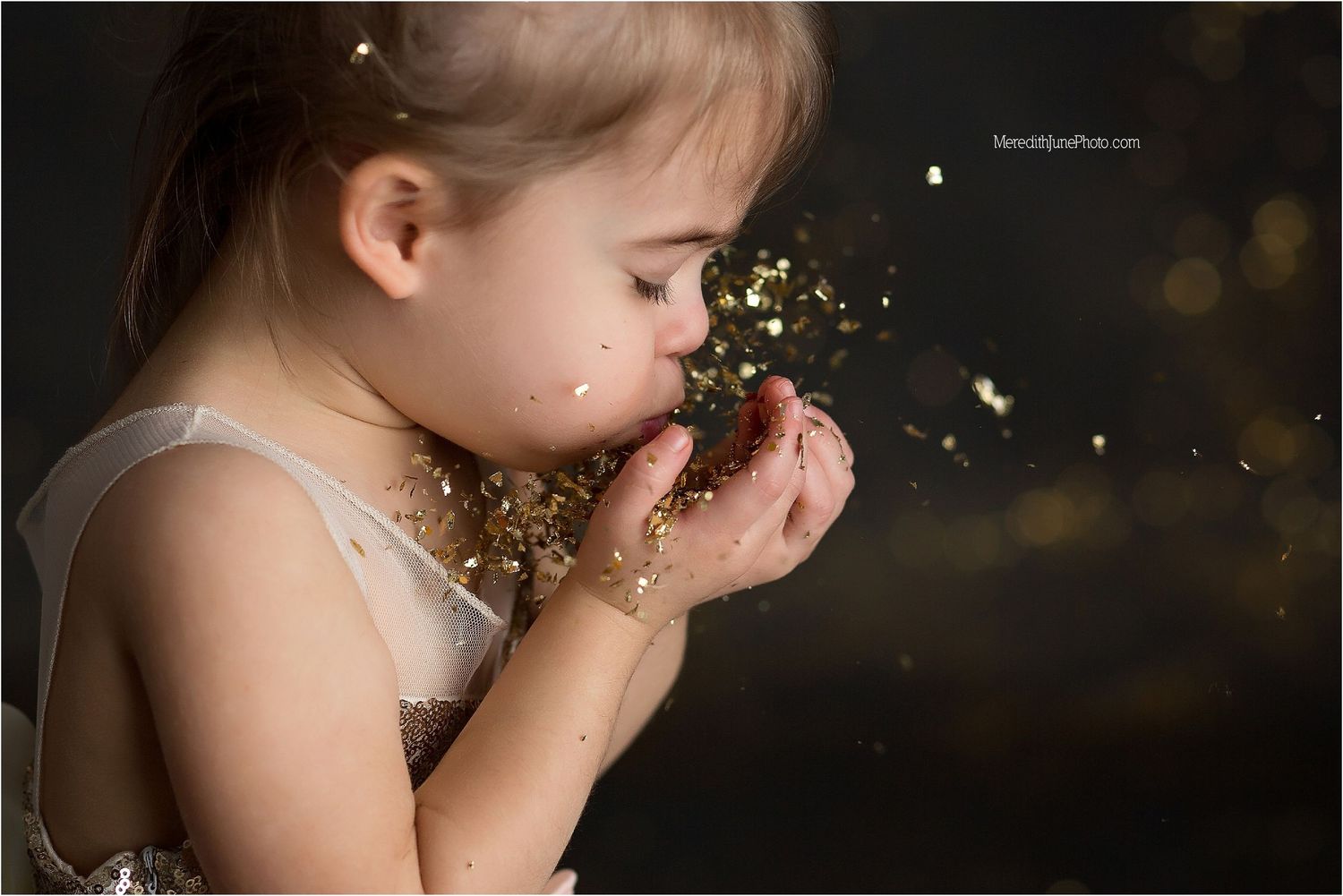 Gold glitter sparkles in the air against a dark background creating a magical atmosphere.