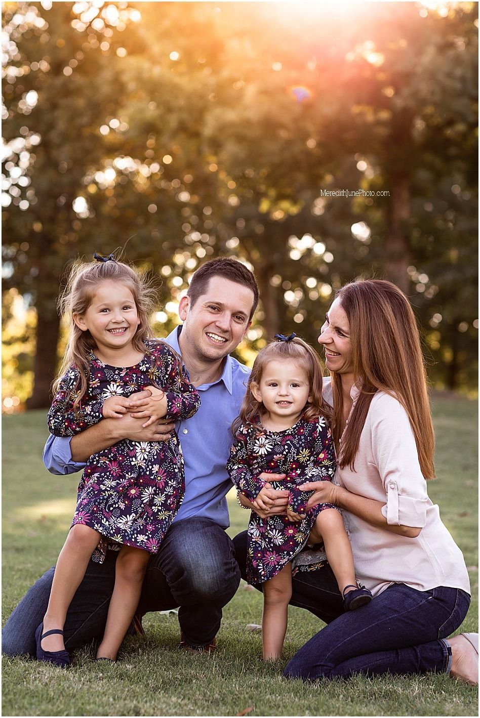 A family poses together outdoors at sunset with beautiful golden bokeh lighting in the background.