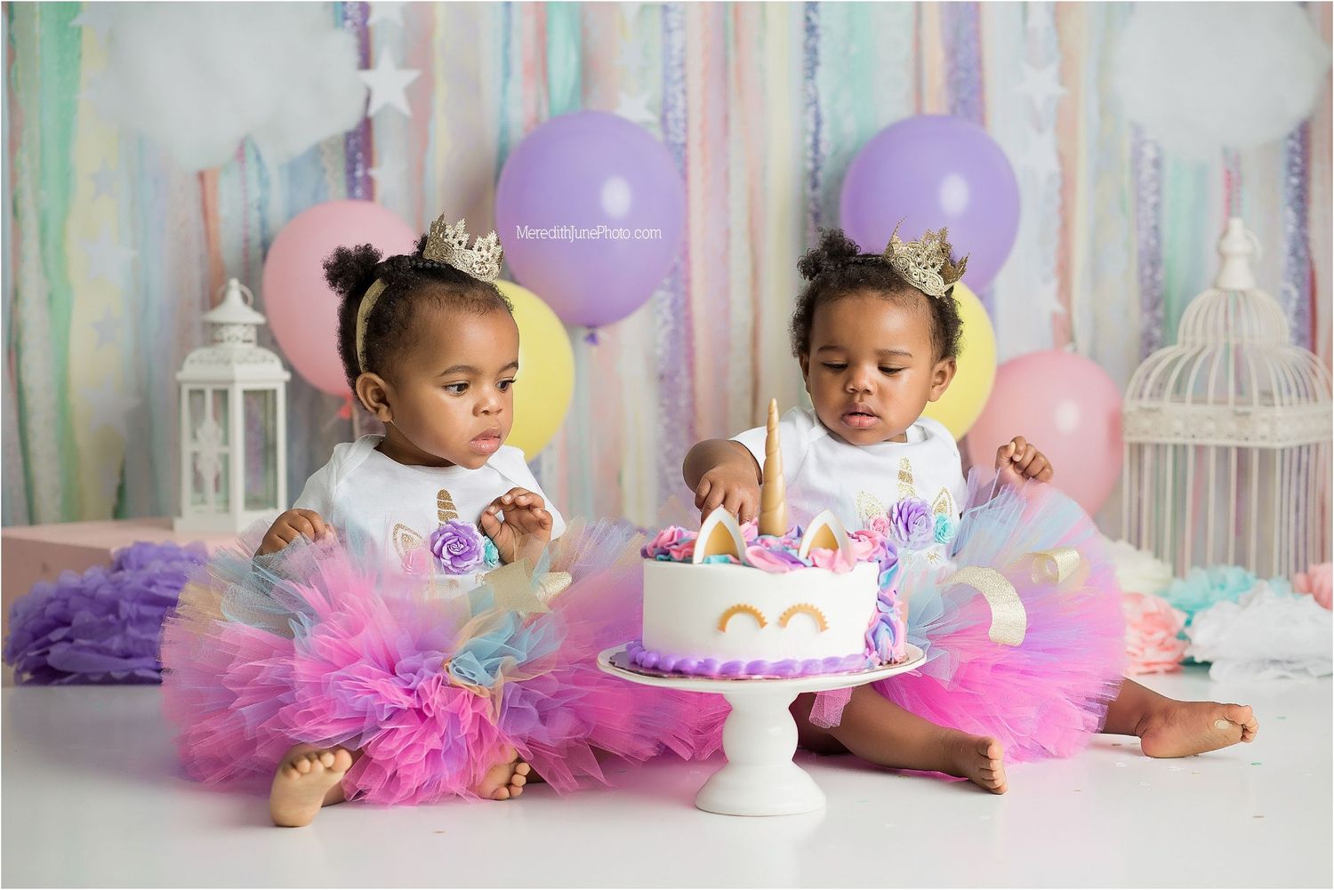 Baby smash cake photo session with pink and purple decorations featuring tulle tutus and birthday balloons.