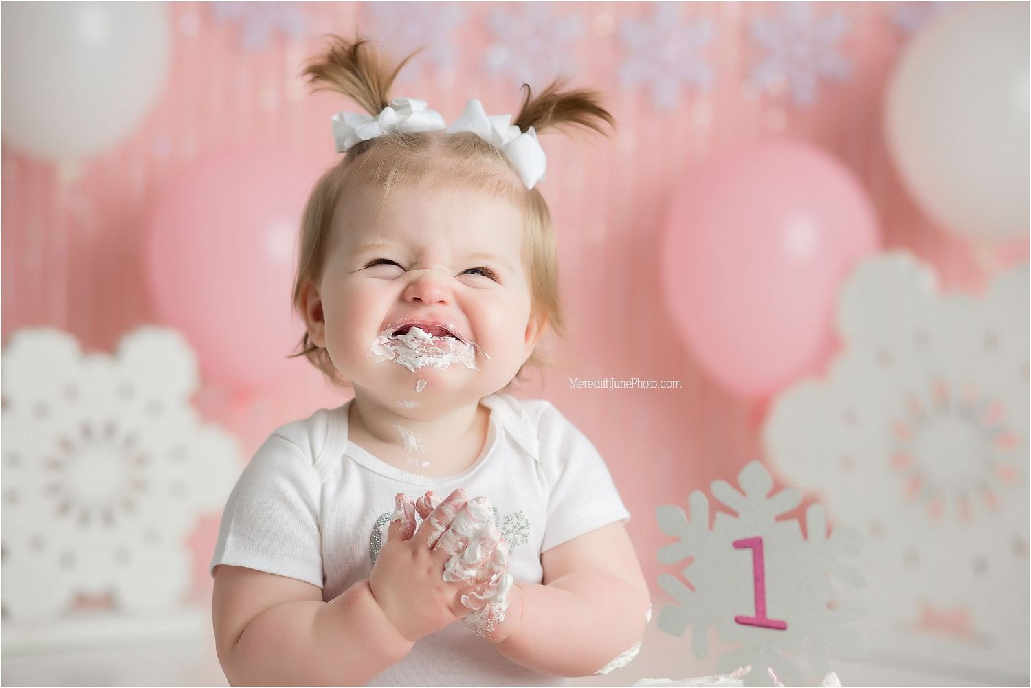 A sweet cake smash photo session with pink balloons and decorations for a first birthday celebration.