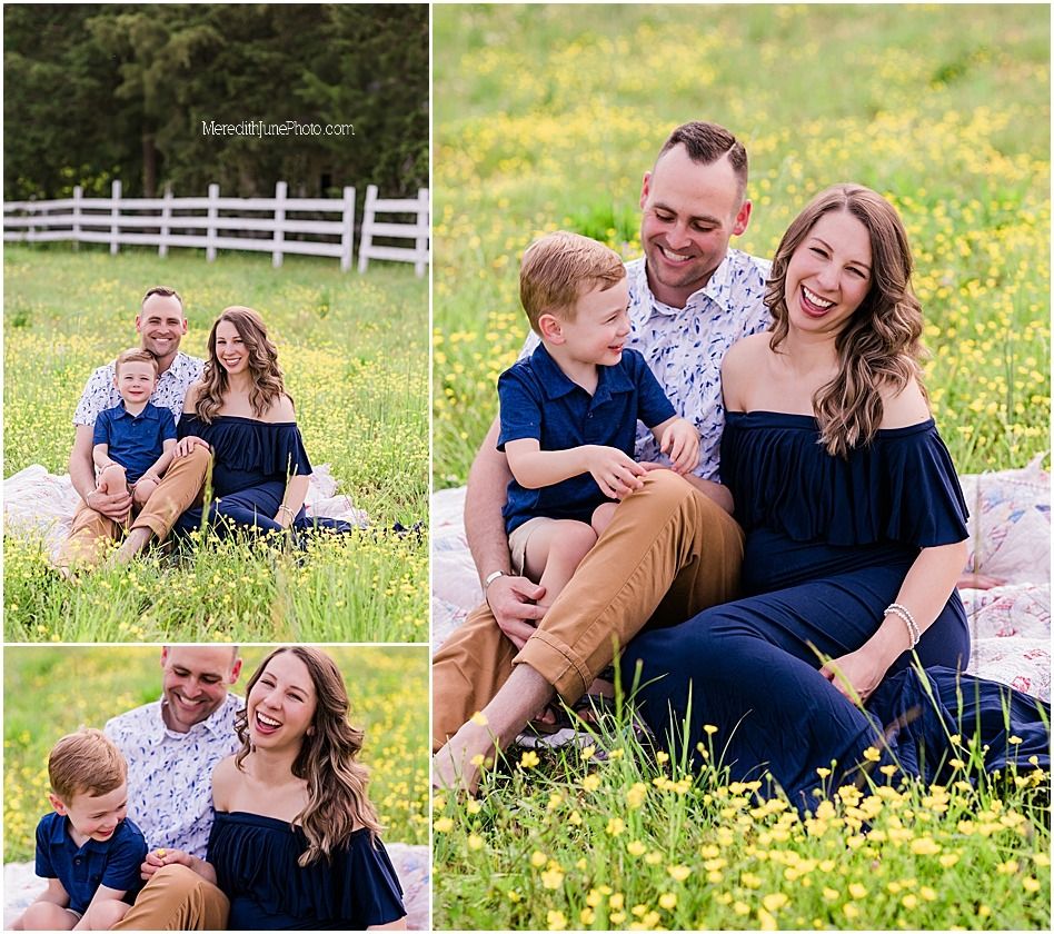 Family enjoying a playful moment together in a sunny meadow with yellow wildflowers and white fence in background.