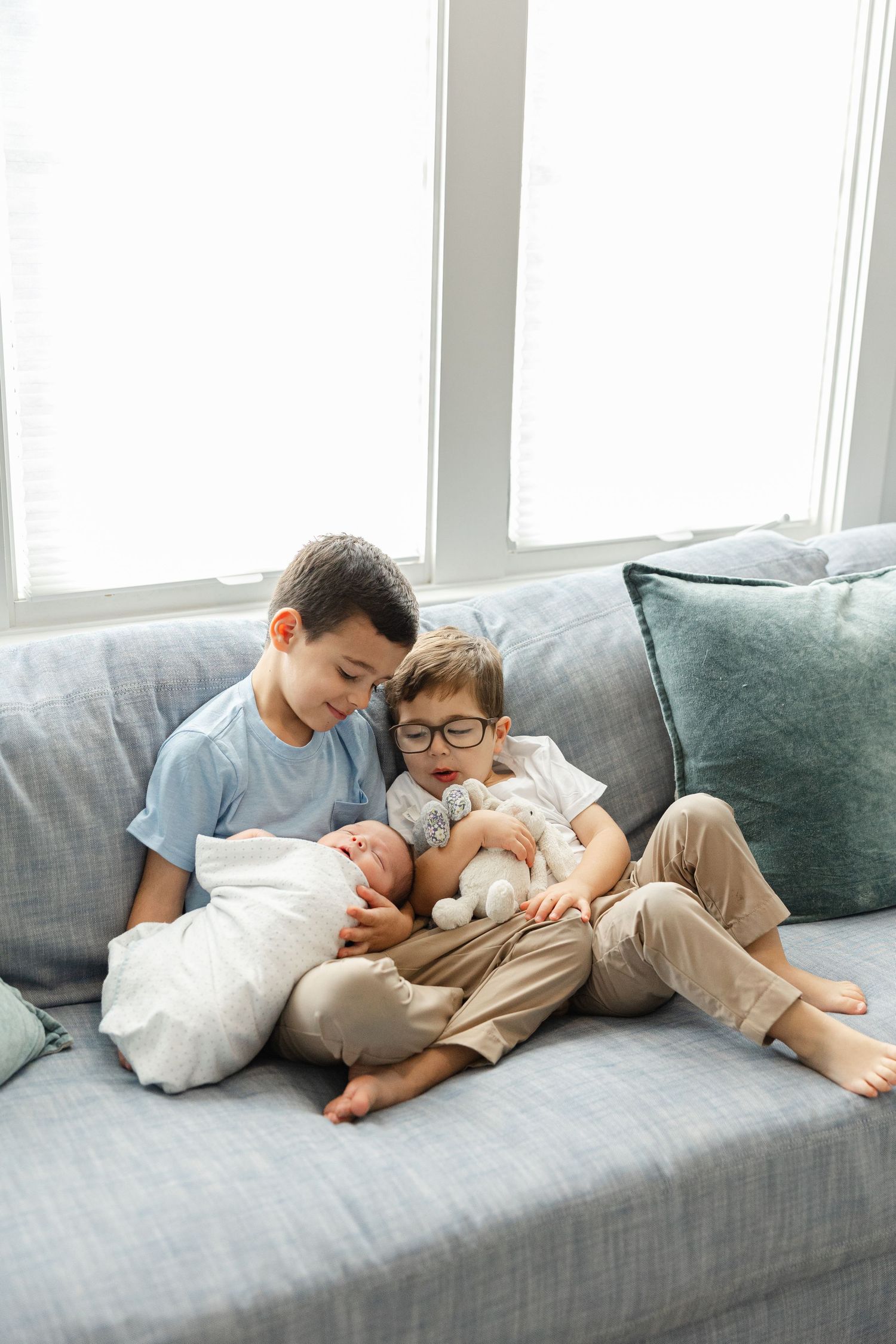 A series of four connected images showing tender moments of affection between a parent and child on a gray couch.
