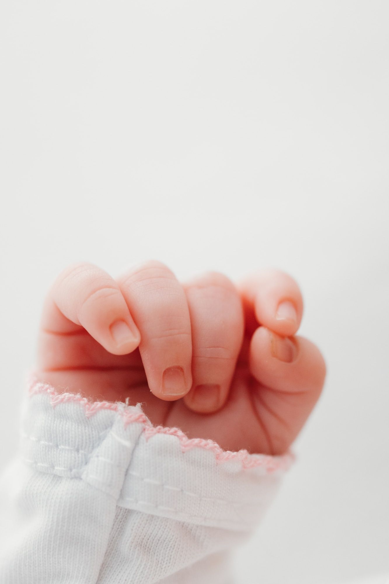 Tiny newborn baby feet in white socks against light background.