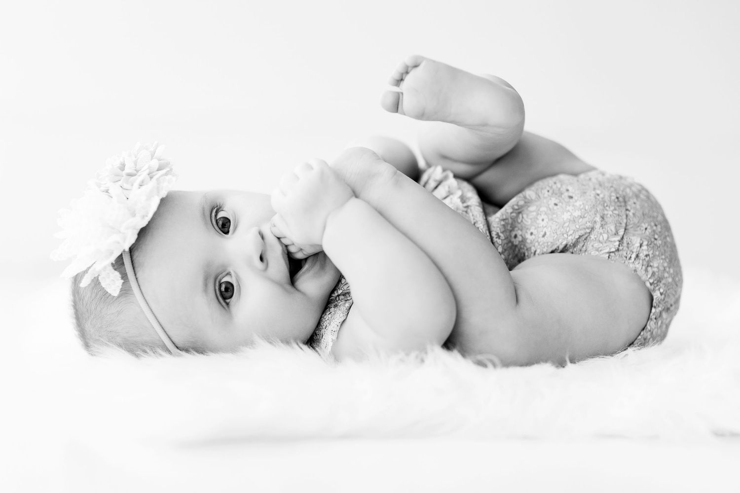 Black and white portrait of baby lying on soft white background.