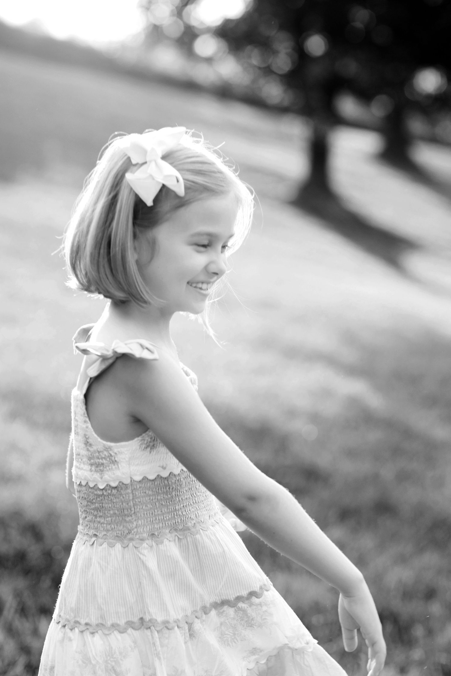 Black and white photos of young child in white dress playing outdoors.
