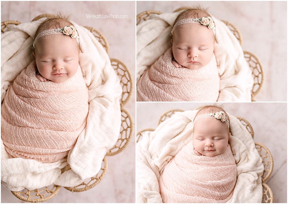 A sleeping newborn wrapped in soft pink swaddle blanket rests in a delicate lace basket.