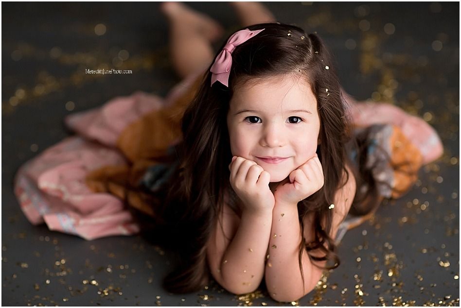 A series of six artistic portrait photos featuring a child in a pink dress against a dark background with gold glitter.