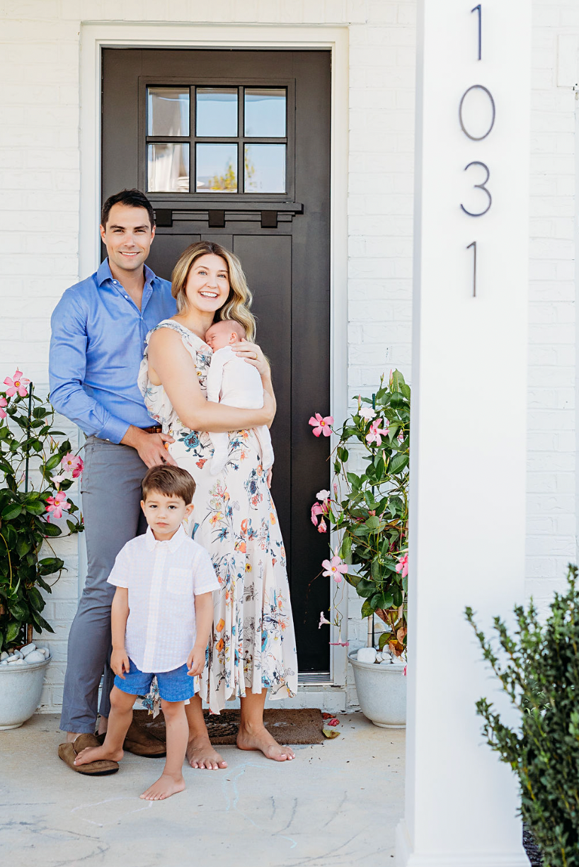 Family standing at front door of house number 1031 with pink flowers.