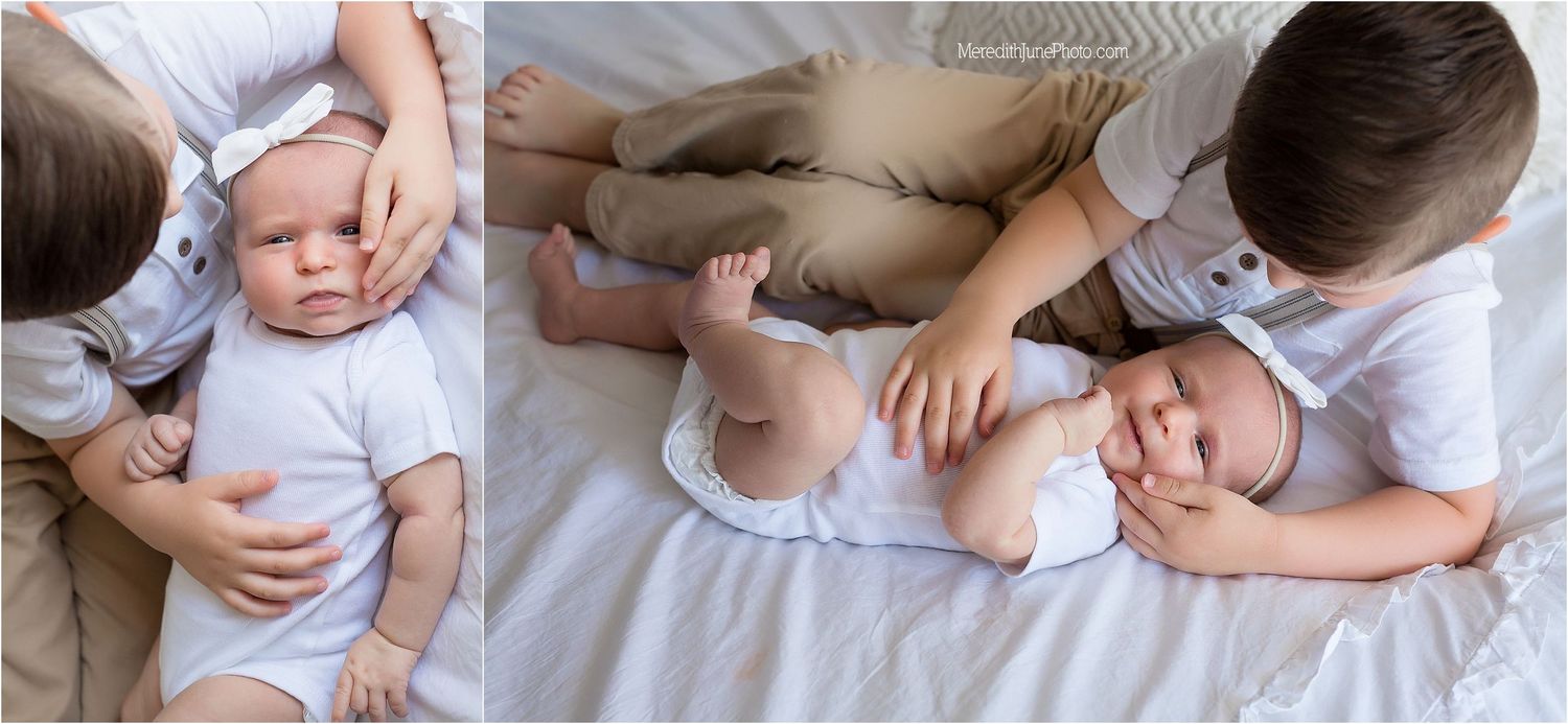 Baby lying on white bedding while being gently touched and comforted.