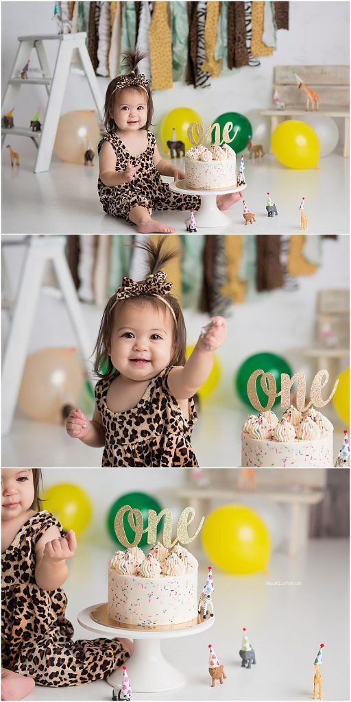 Baby in leopard print dress celebrating first birthday with decorated cake and balloons.