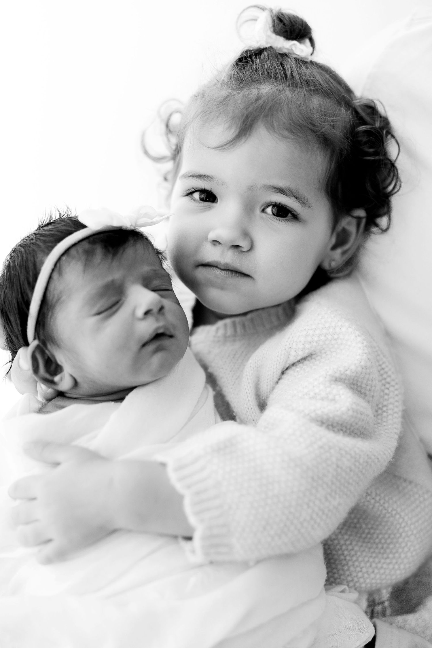 A series of black and white photos showing two young children sharing tender moments while lying down together.