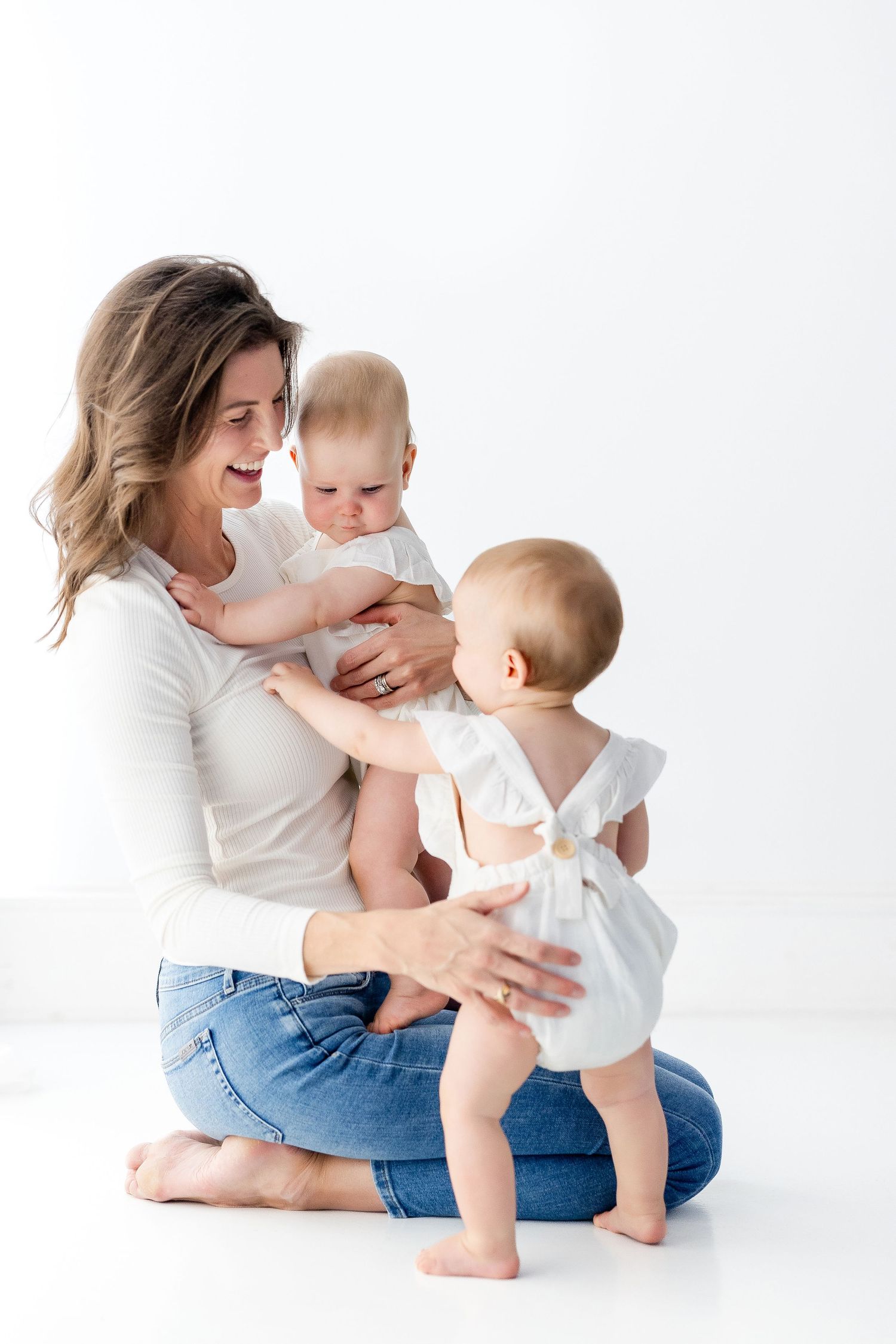 Parent and baby share playful moments in casual attire against white background.