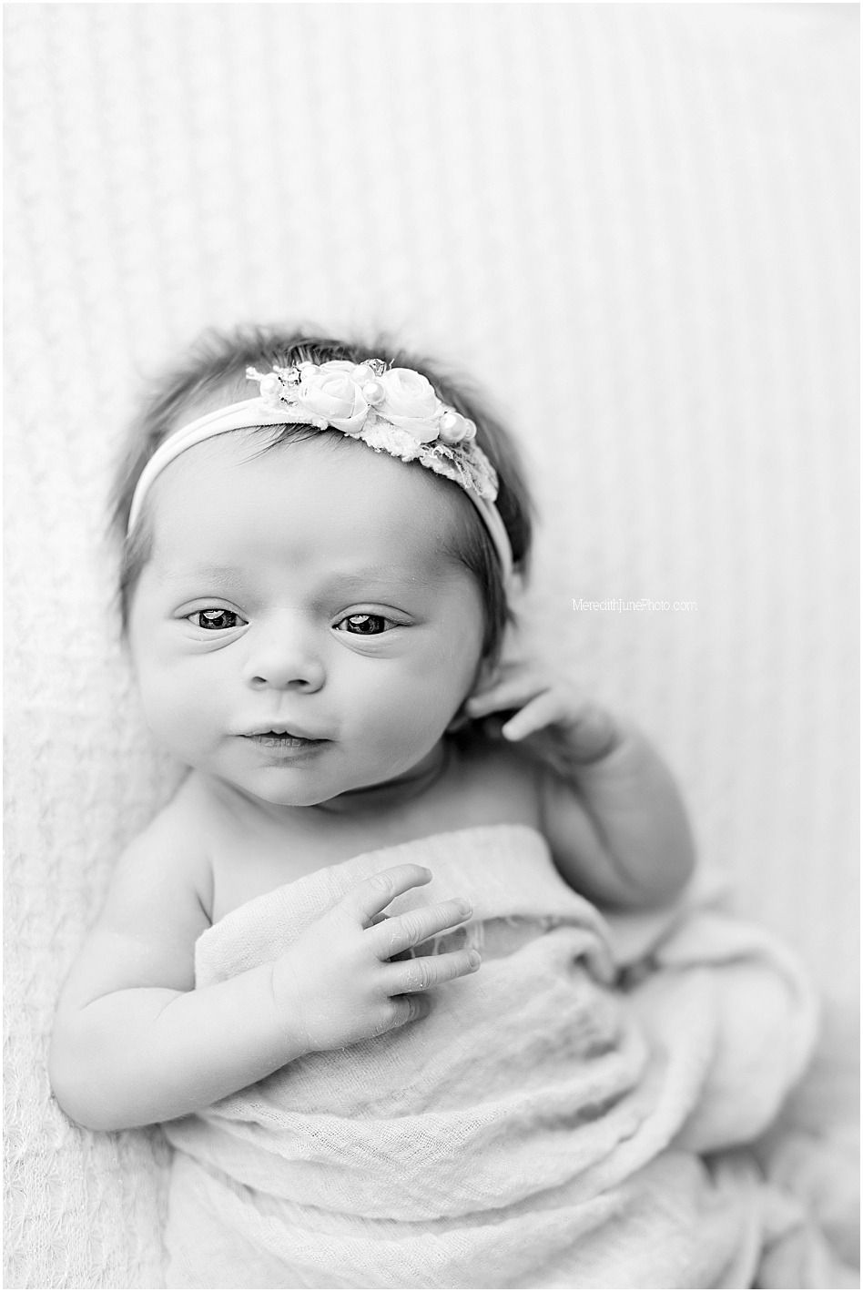 Black and white portrait series of a baby wrapped in soft white blankets with delicate floral headband.