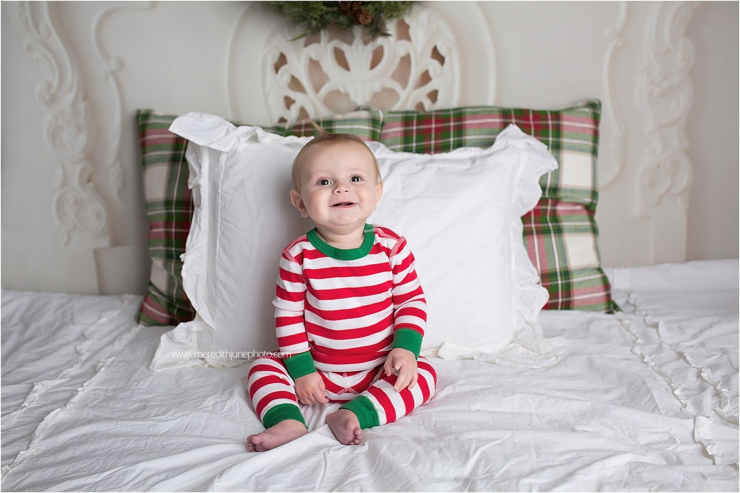 Cozy Christmas bedroom featuring plaid accent pillows and white bedding against a decorative wall.
