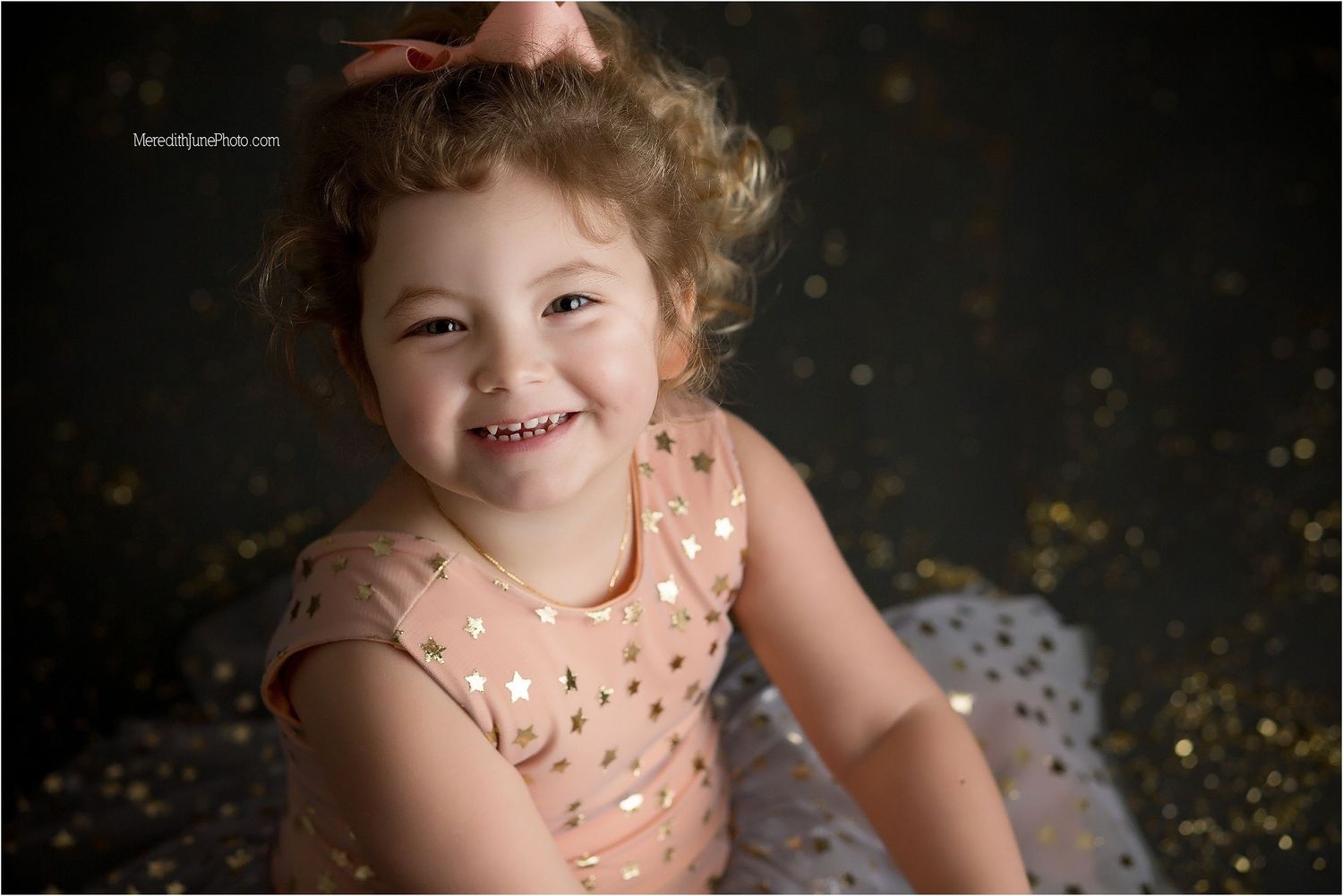 A joyful portrait with glitter and a peach-colored dress against a dark backdrop.