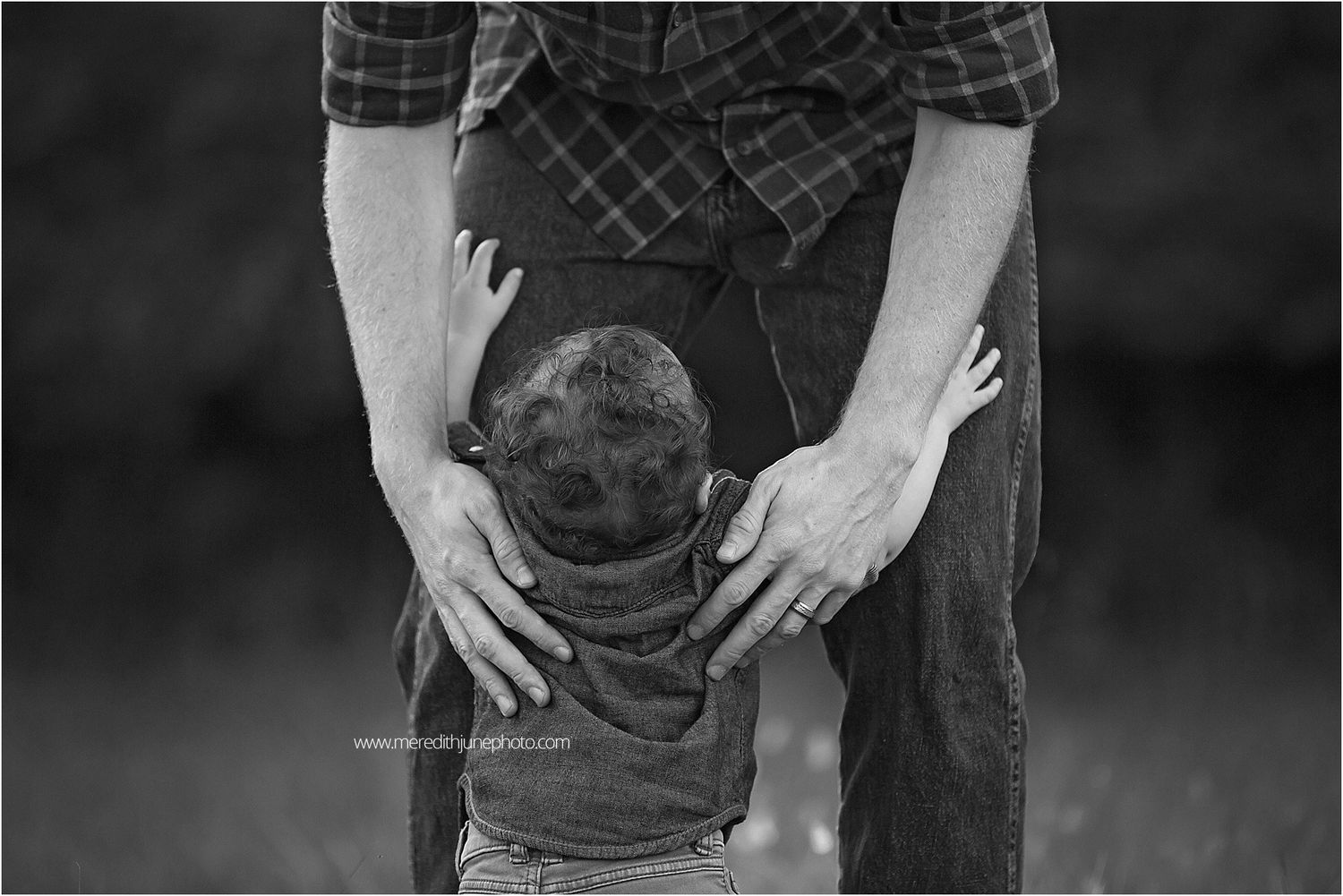 A tender moment between parent and child during an outdoor photoshoot in black and white.