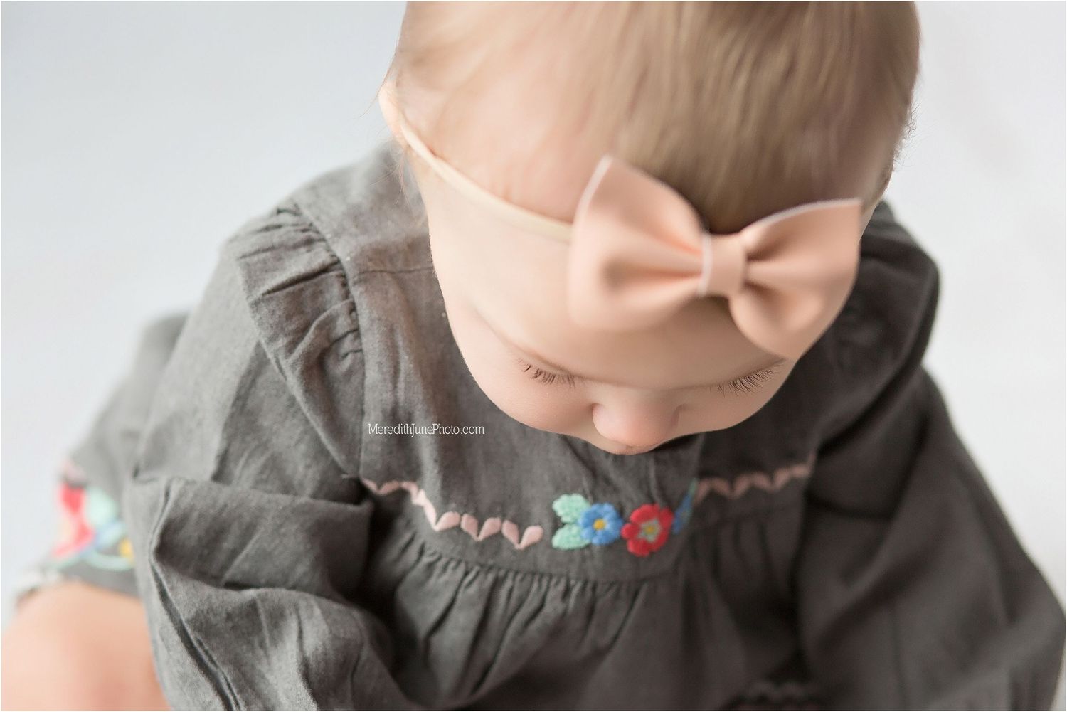 A person wearing a gray hoodie with a colorful embroidered design across the neckline.