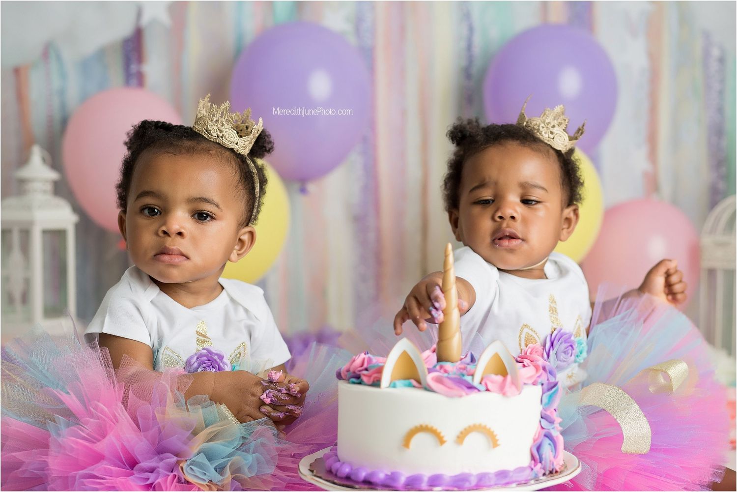 Baby in pink tutu dress celebrates first birthday with cake smash photoshoot surrounded by pastel balloons and decorations.
