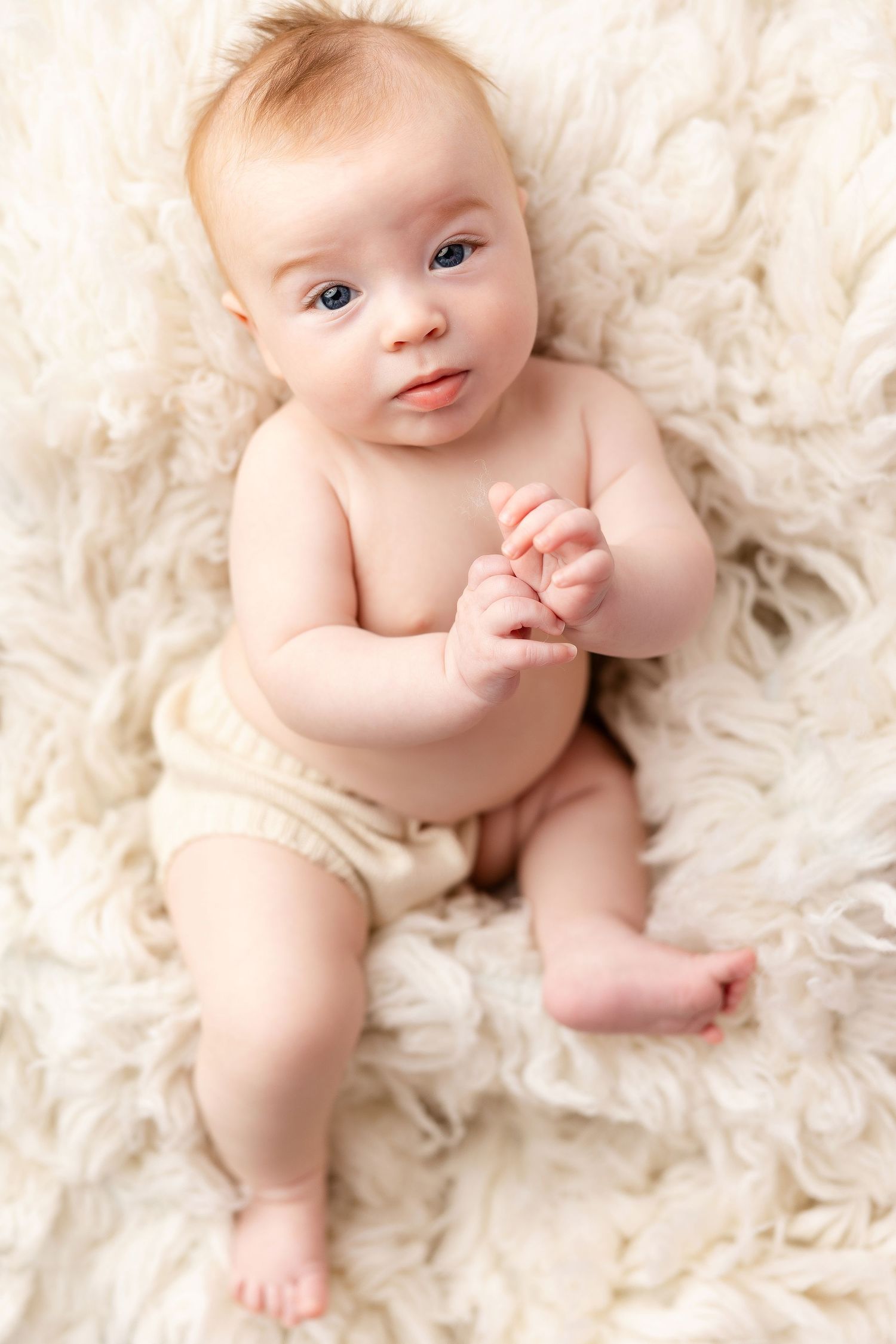 A series of sweet baby portraits on a cream-colored fluffy rug showing different adorable poses.
