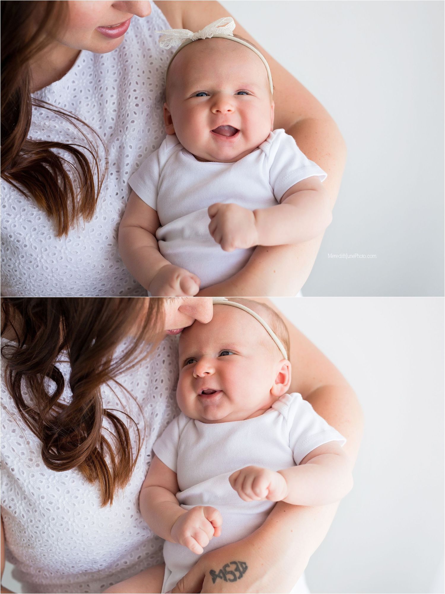 A baby wearing a white onesie smiles joyfully while being held in arms wearing a white lace dress.