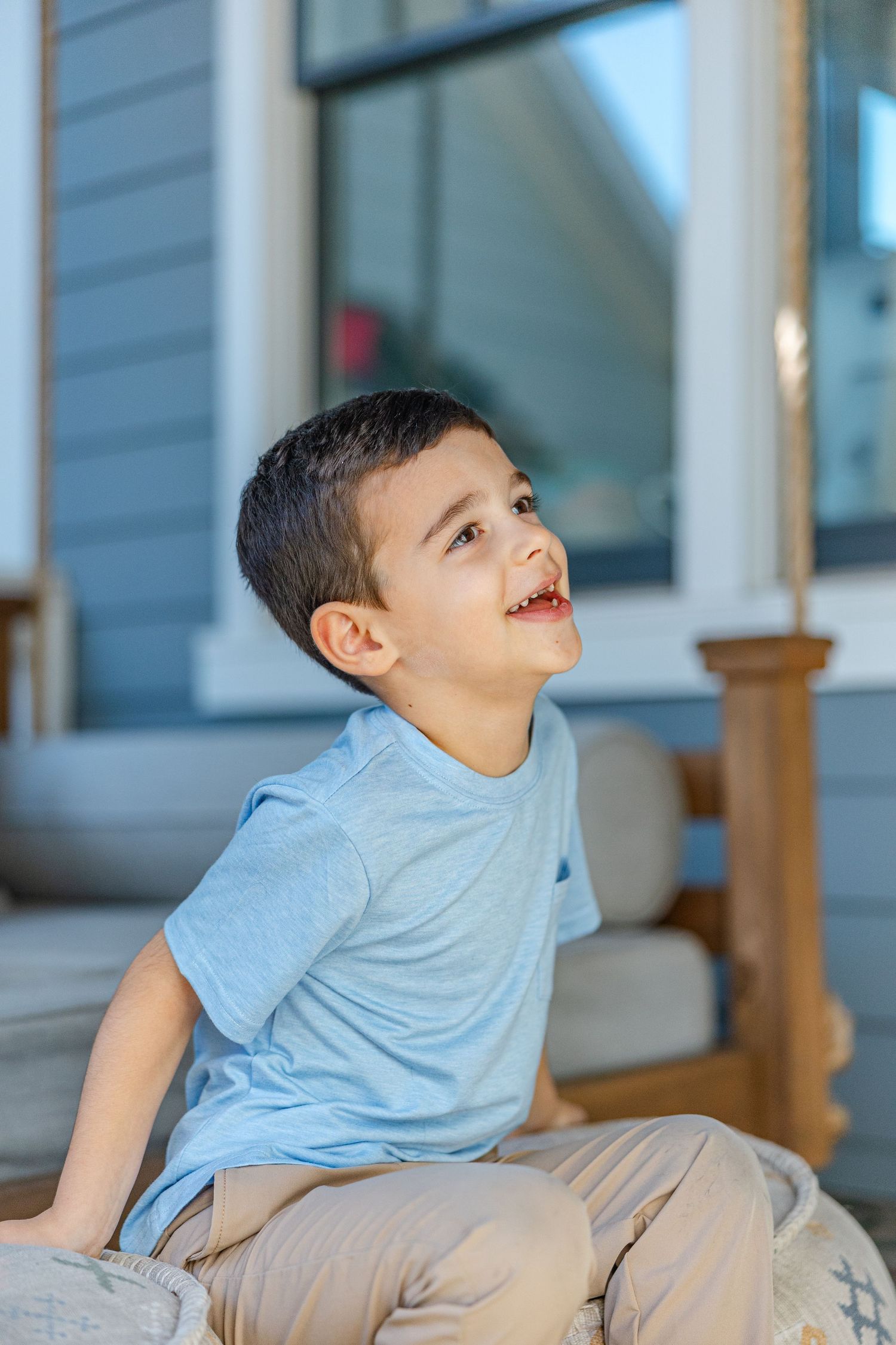 Child in light blue t-shirt sitting on porch steps in progressive action shots.