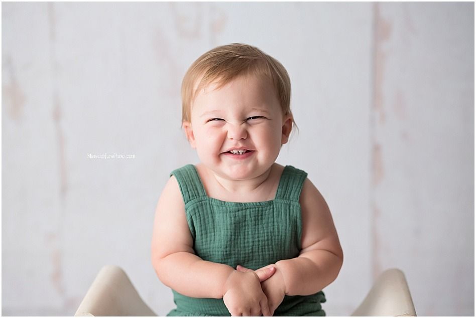 A series of connected photos showing a baby in a green outfit sitting and smiling against a white backdrop.
