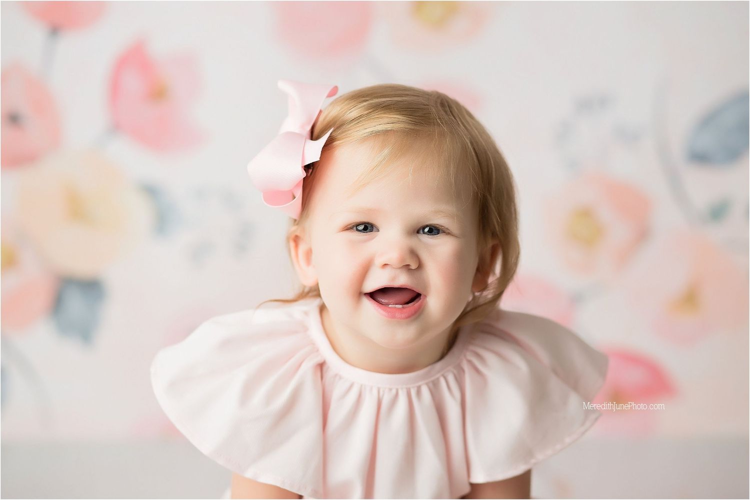 A series of joyful baby portraits with pink floral backdrop and ruffled dress.