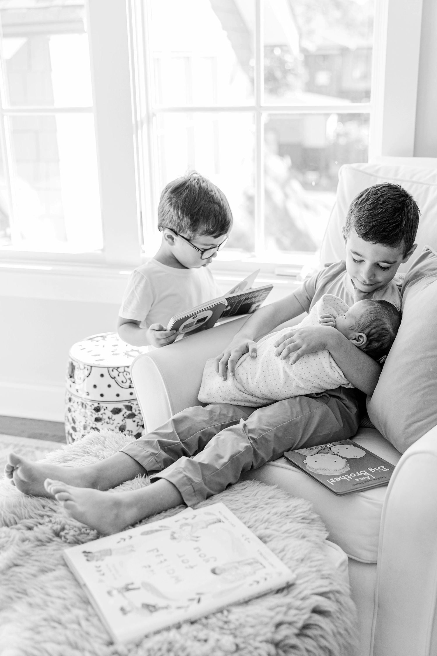 Black and white photo series showing siblings reading together on a couch in a bright sunlit room.