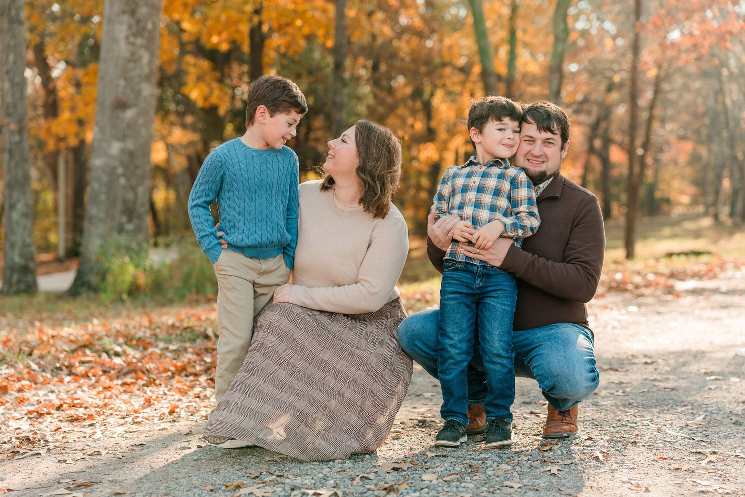 Family relaxing together on autumn ground with fallen leaves.