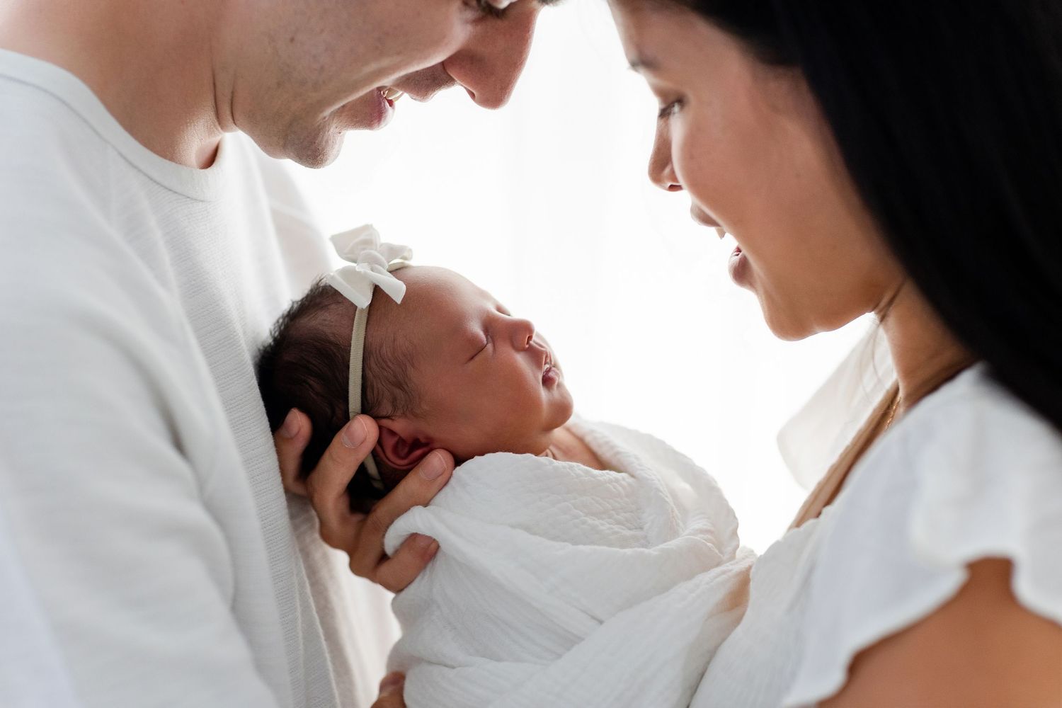 A series of tender black and white photos showing parents cradling and bonding with their newborn baby.