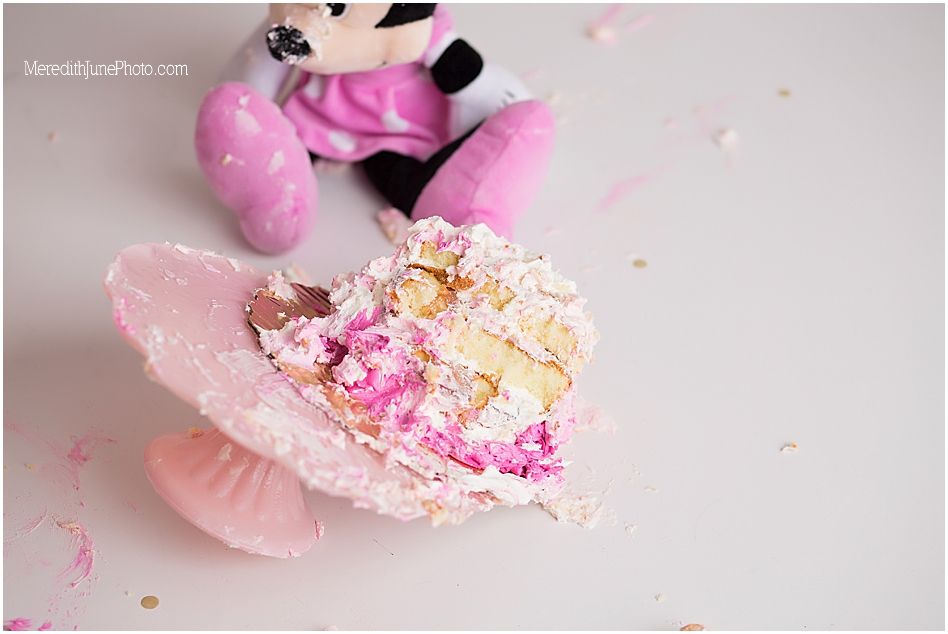 A pink and white ruffled tutu with glitter and sparkles lies on a light gray surface next to a plush toy.