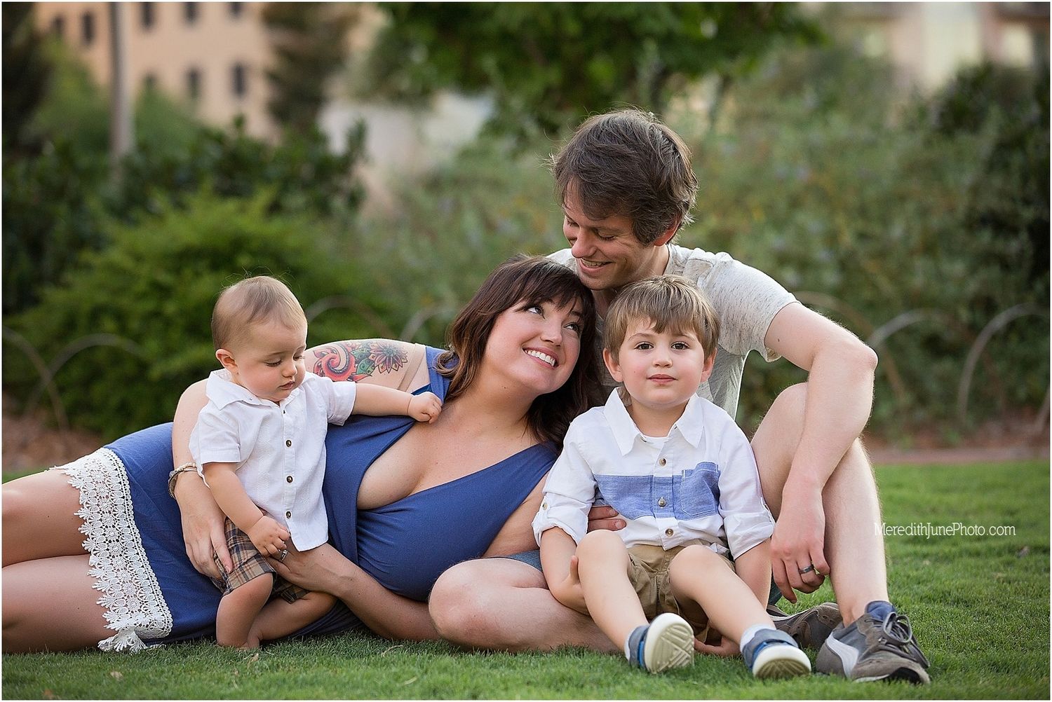 Family relaxing together on green grass during golden hour outdoor photography session.