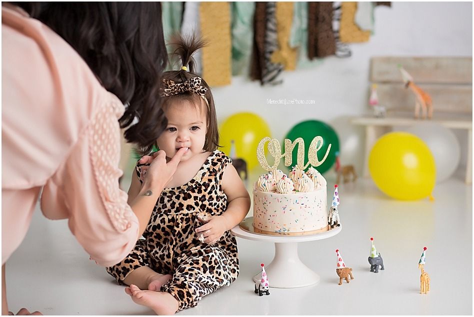 First birthday celebration setup with cake, balloons and safari animal decorations.