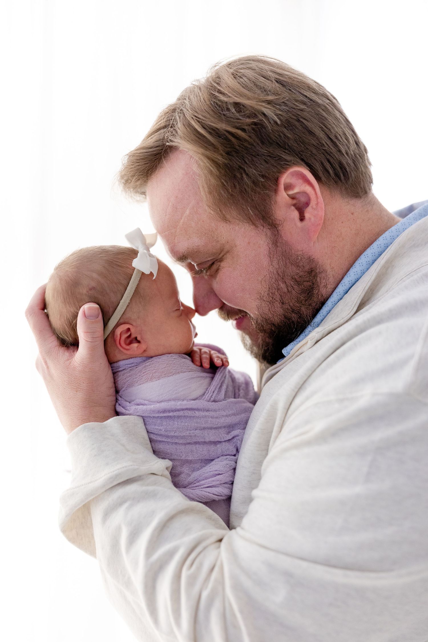 An intimate black and white photograph of a parent cradling and bonding with their swaddled newborn baby.