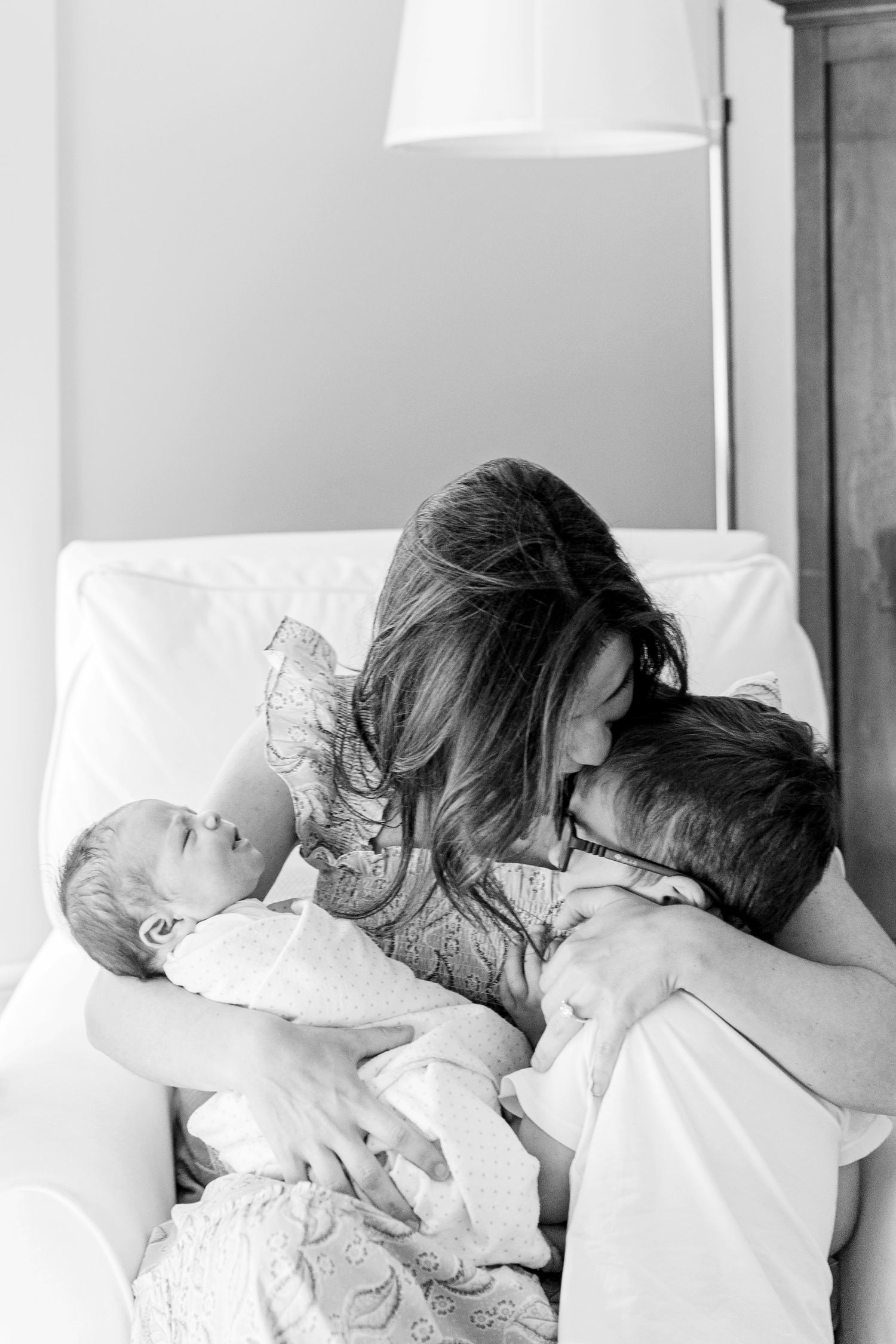Sleeping children nestled together in white bedding in a cozy bedroom setting.