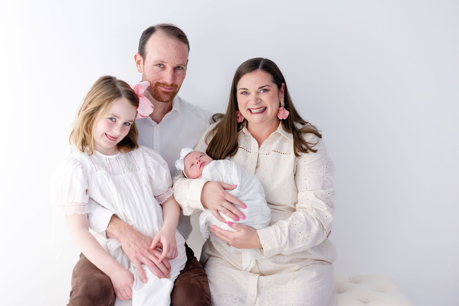 A series of four white-toned family portrait photos showing tender moments between parents and children against a light background.