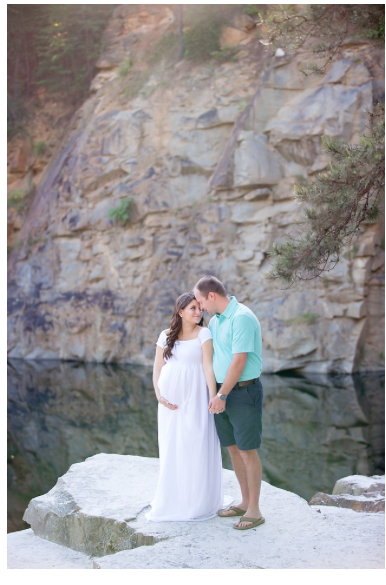 Romantic couple photography session at a quarry with white dress and teal shirt against rocky cliffs and water backdrop.
