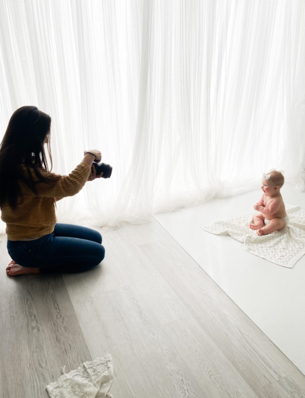 A series of photos showing a baby lying on a white blanket being photographed from different angles on a hardwood floor.