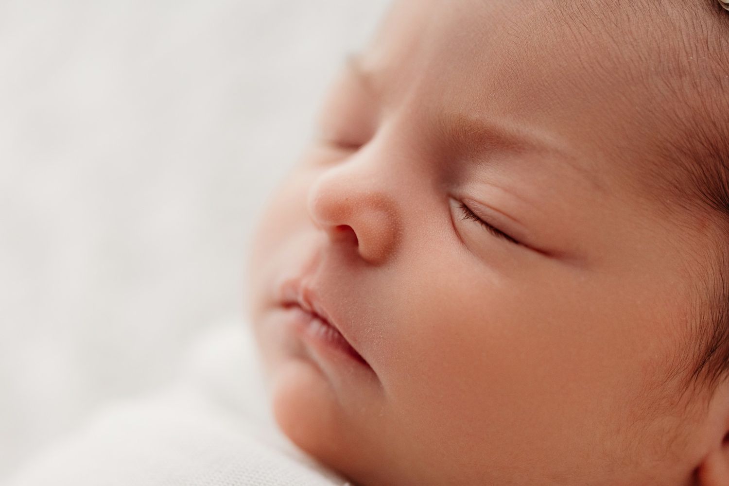 Close-up view of a sleeping newborn baby's face in soft natural light.