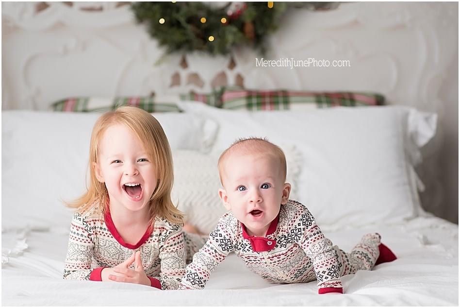 Festive holiday photos on white bedding with plaid pillows and Christmas decor in the background.