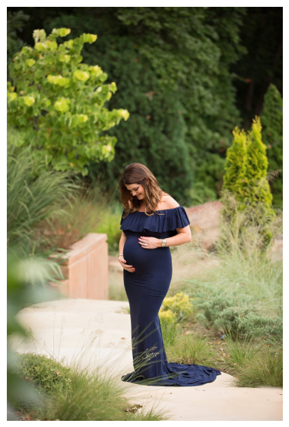 Artistic maternity portraits in a navy blue gown against natural foliage and garden backdrop.