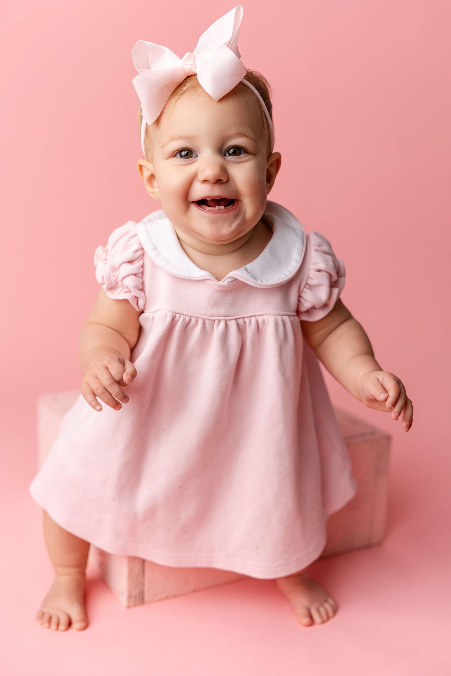 Sweet baby in pink dress and bow sitting against pink background in four adorable poses.