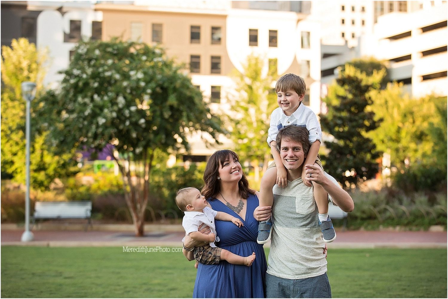A family enjoying a summer evening together in an urban park with city buildings in the background.