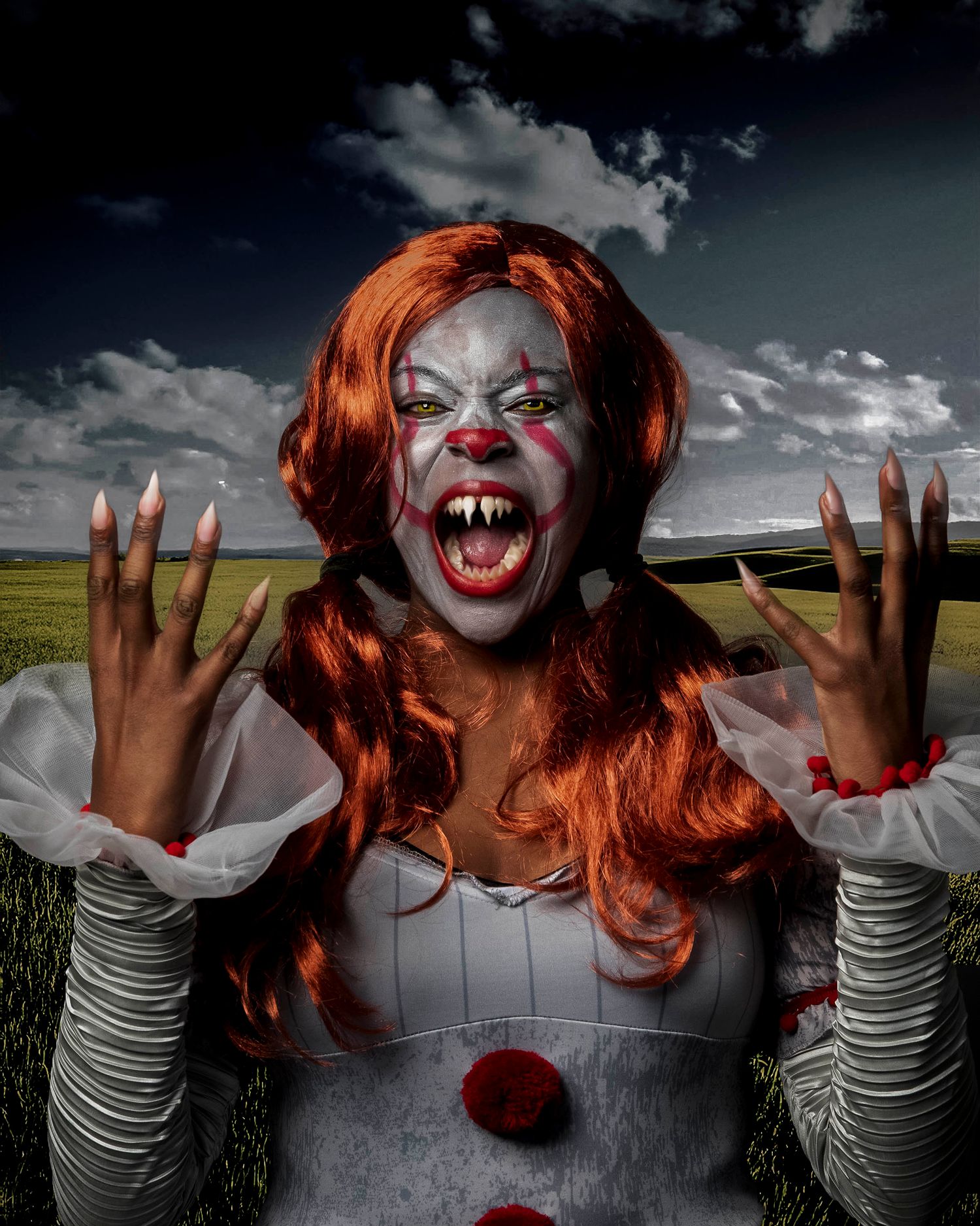 Creepy clown with red hair and white makeup making scary faces against a dramatic sky backdrop.